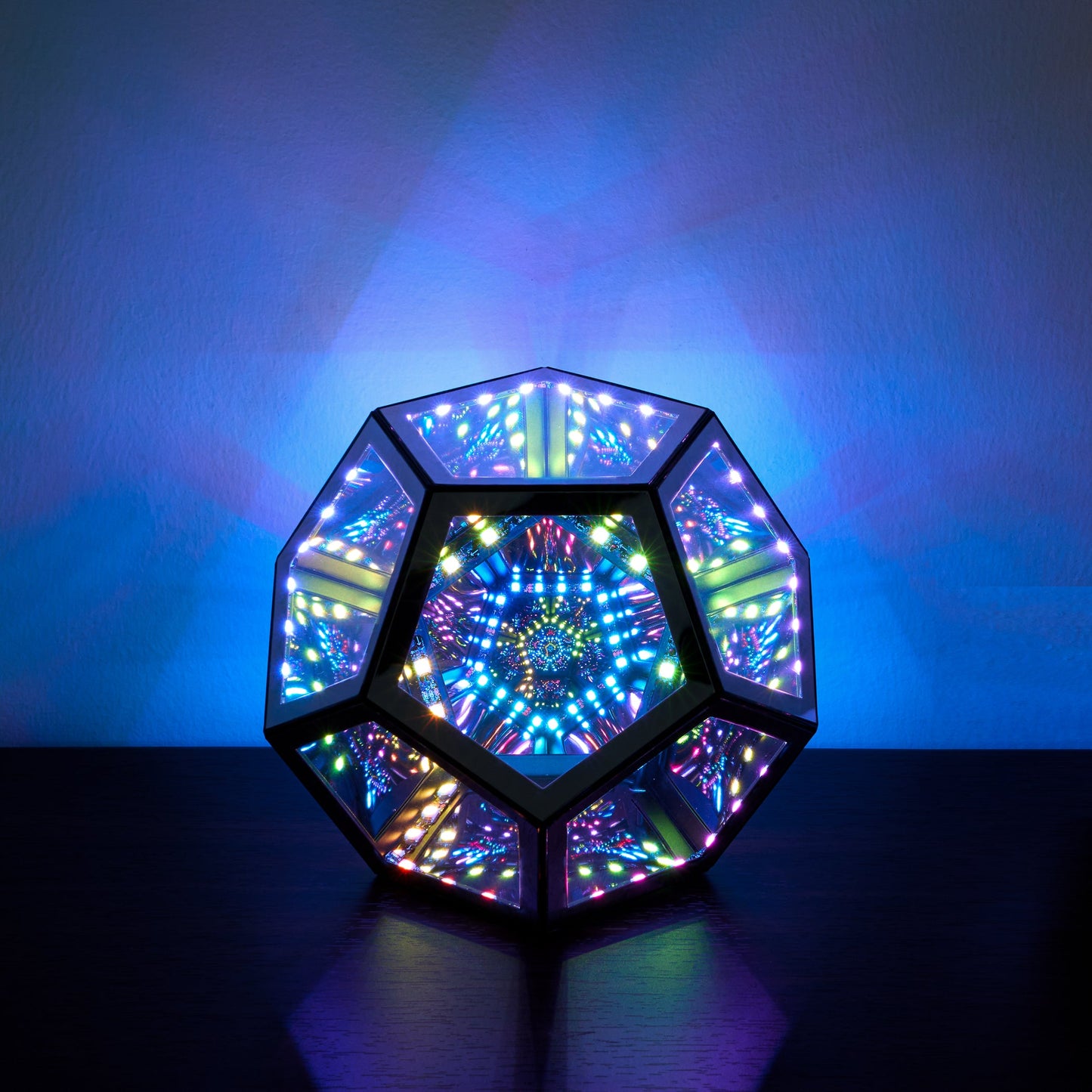 Multicolored geometric light fixture on a dark surface with a blue gradient background