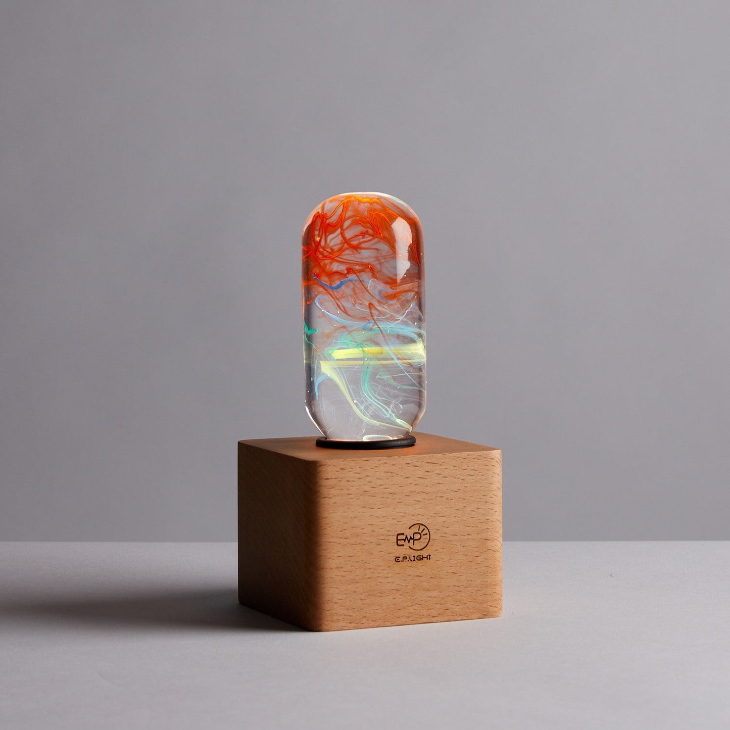 Decorative object with a colorful design on a wooden base against a gray background