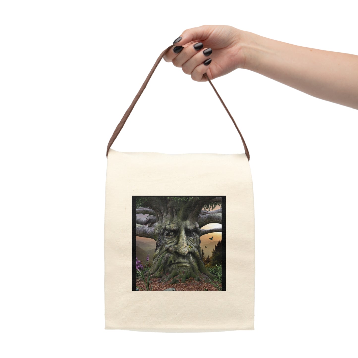 Hand holding a beige tote bag with a nature-themed design on a white background