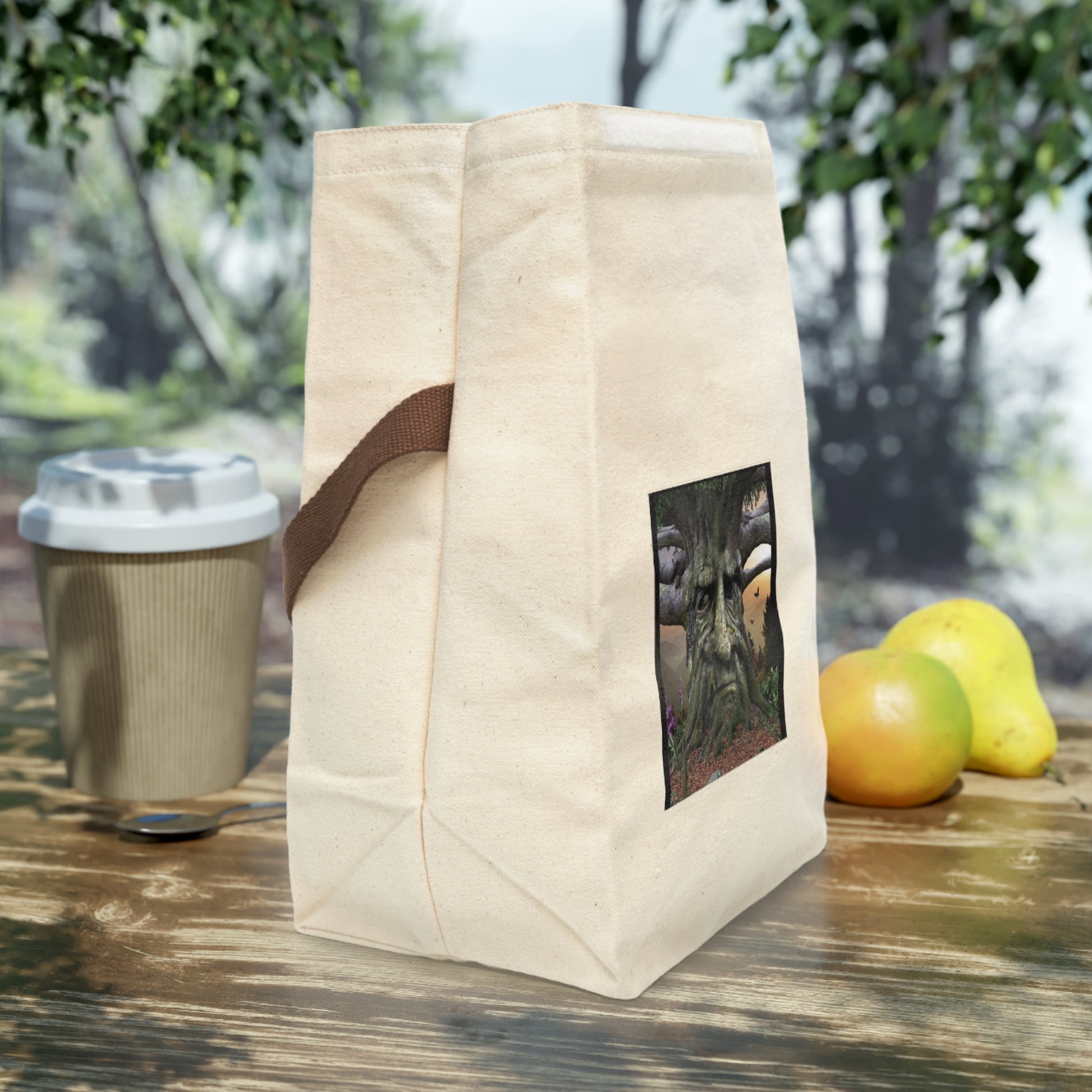 Beige tote bag with a coffee cup and apples on a wooden surface outdoors.