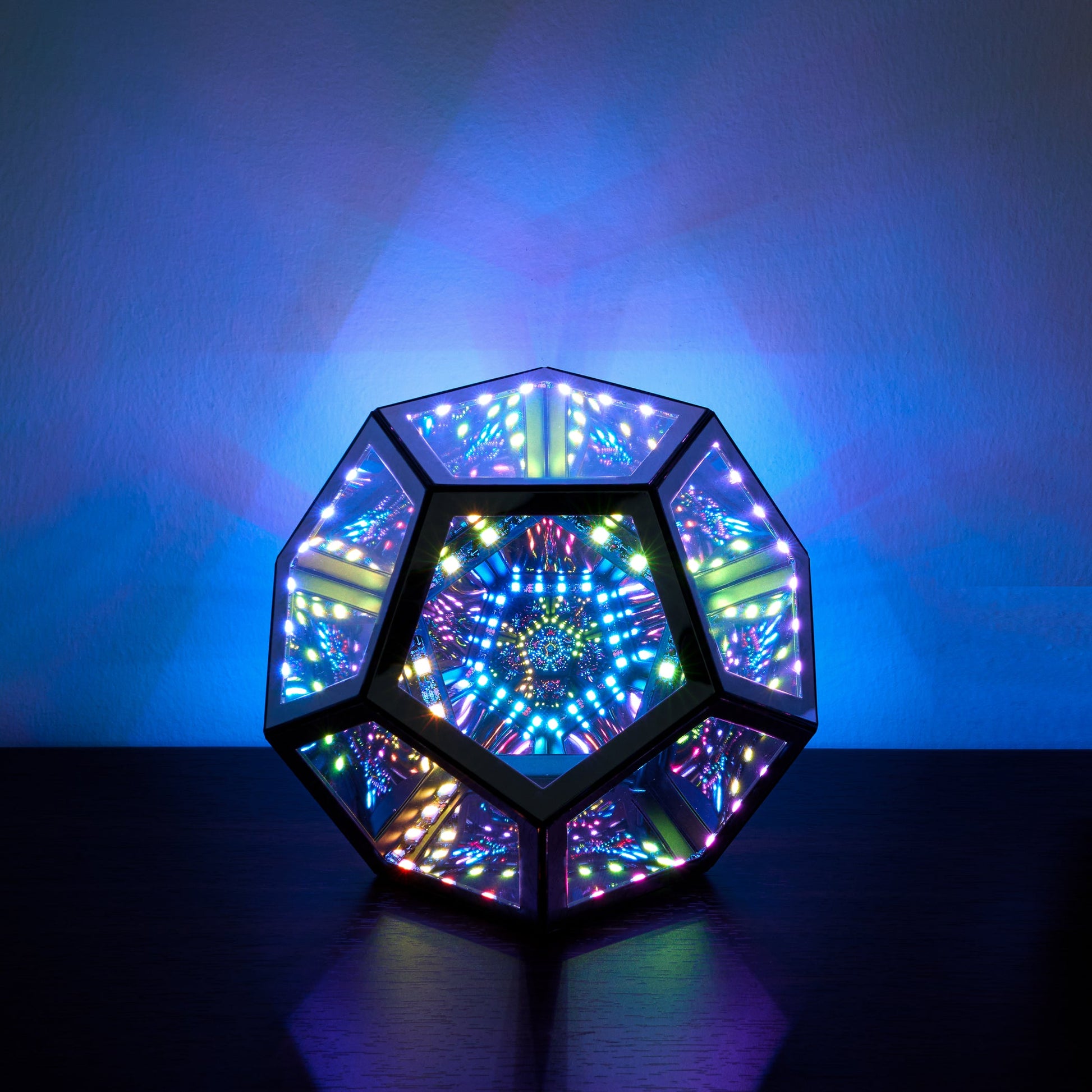 Multicolored geometric light fixture on a dark surface with a blue gradient background