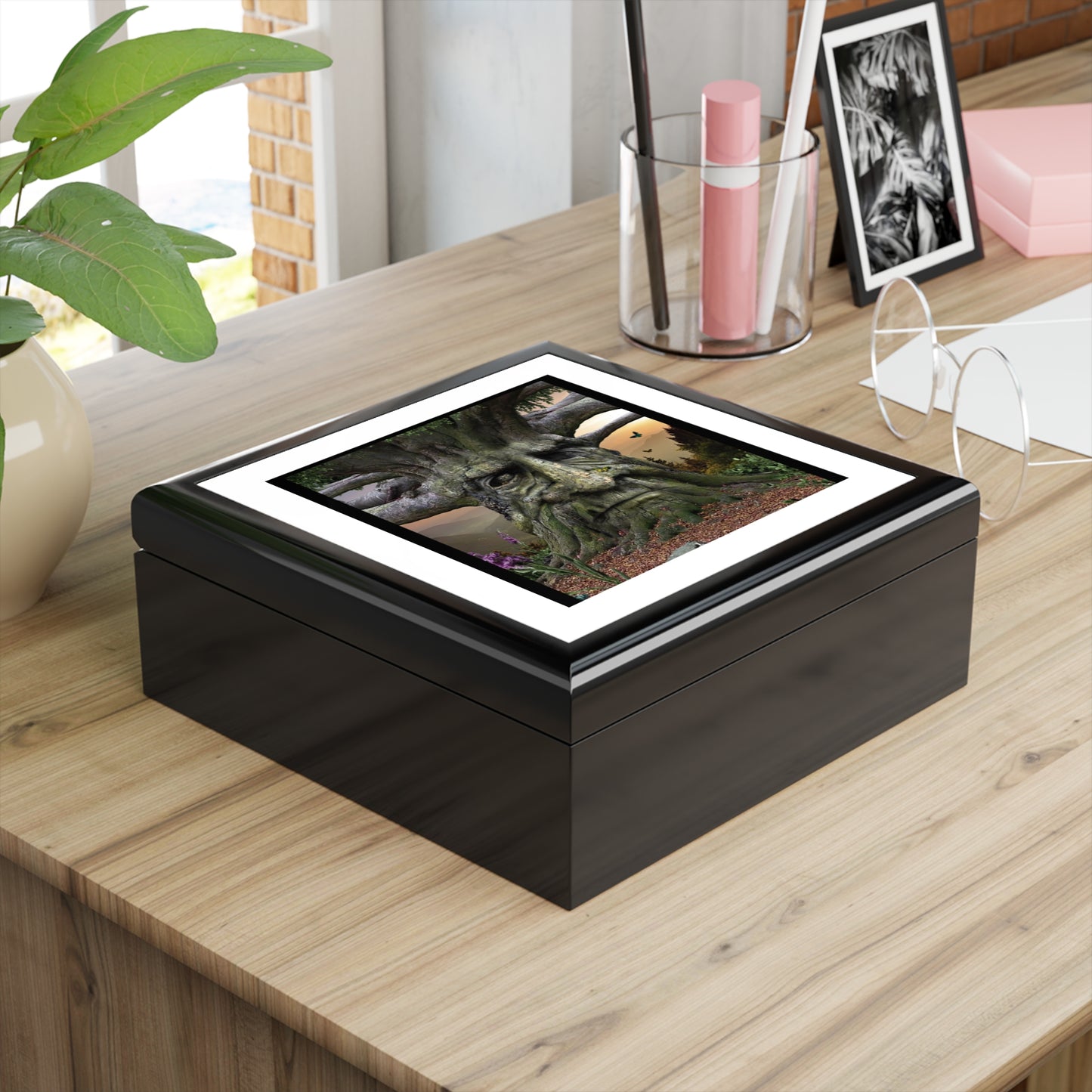 Black rectangular box with a screen on a wooden surface, surrounded by decor items.