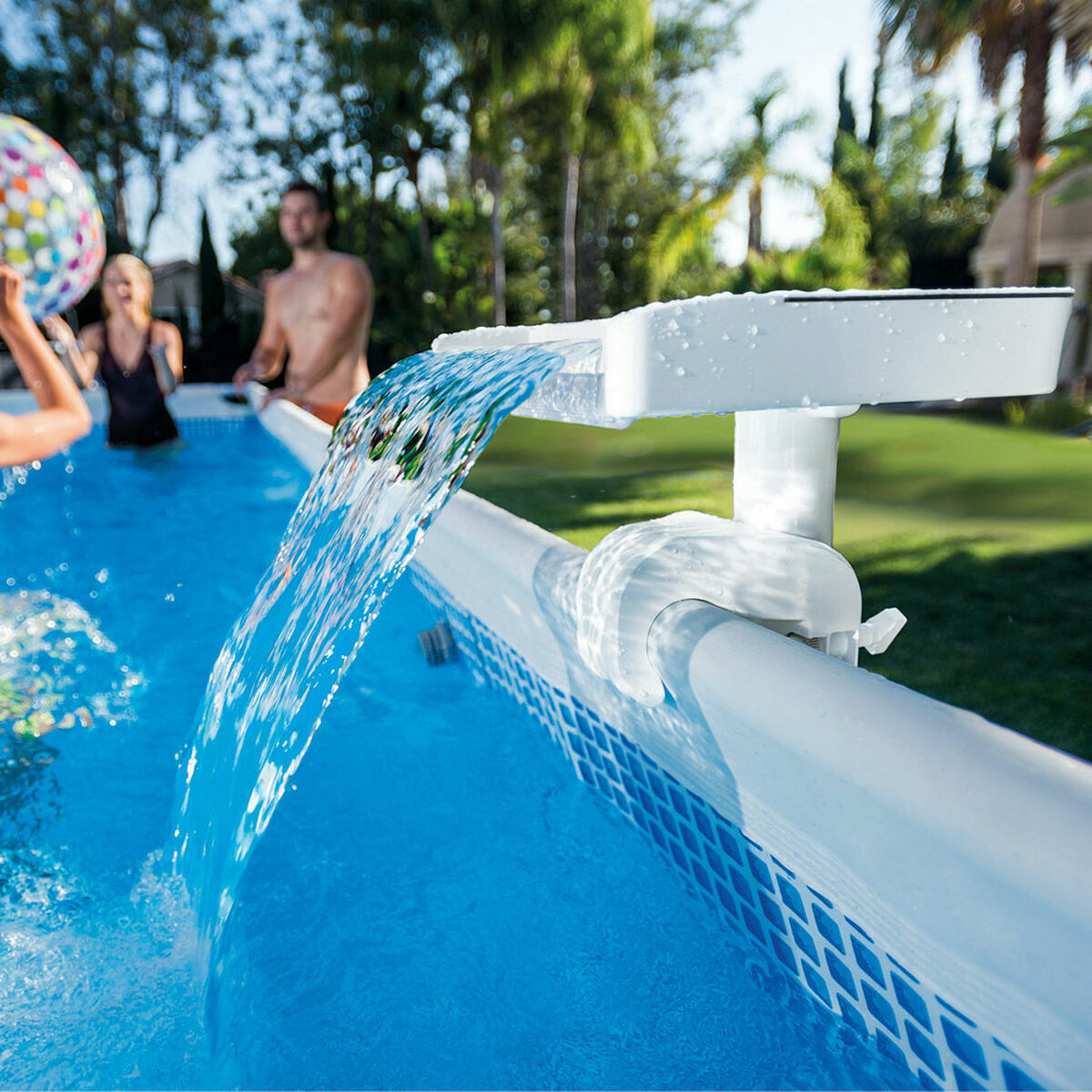 People enjoying a pool with a water feature in a garden setting
