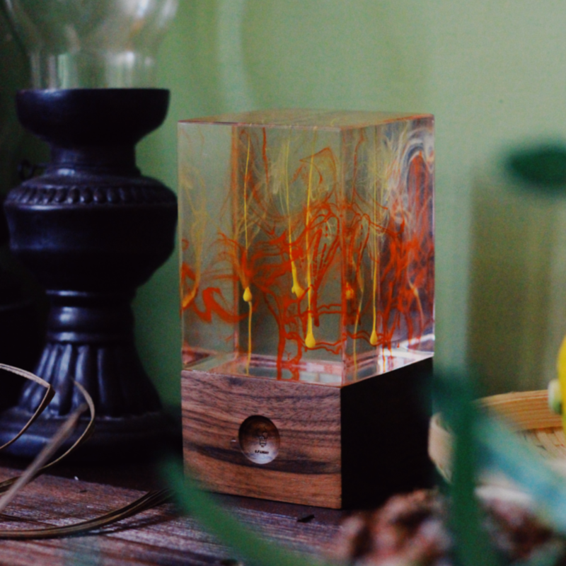 Wooden lamp with orange and yellow design on a wooden surface