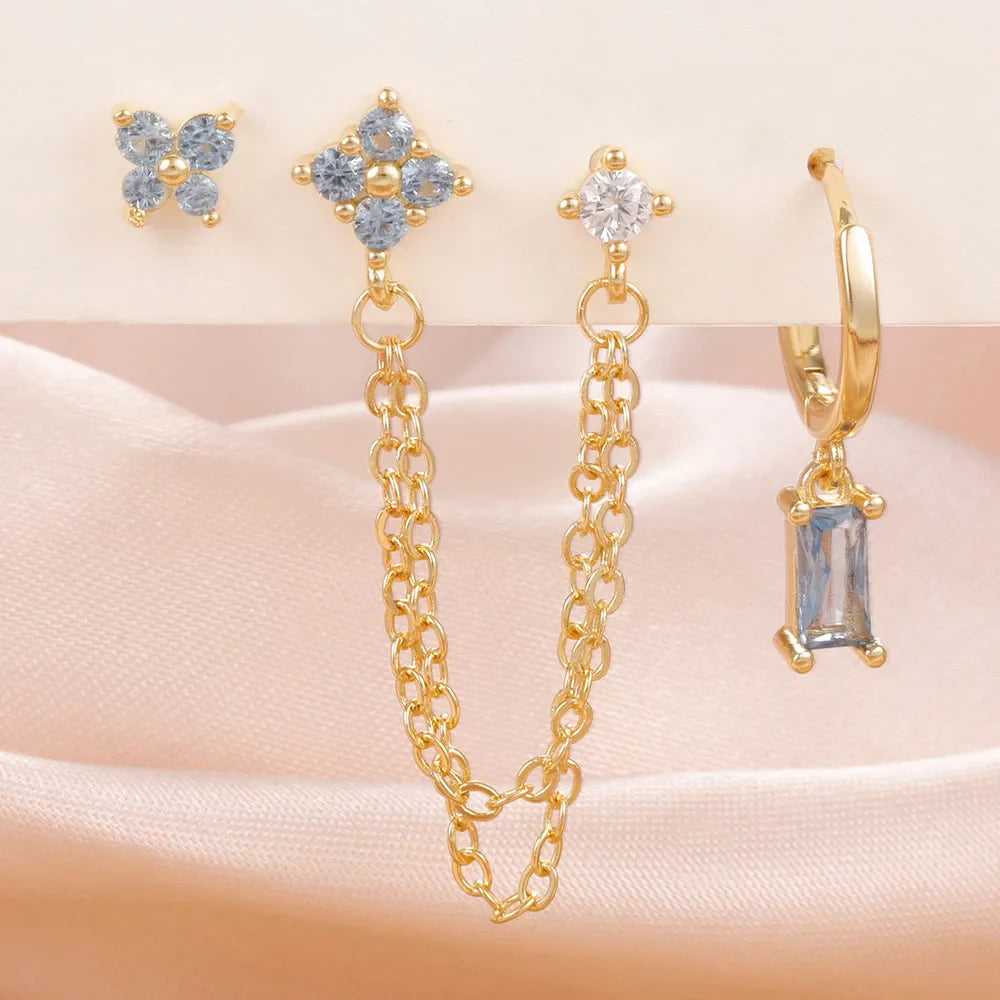 Celestial zodiac birthstone earring set in gold with gemstone accents and elegant chain detail background