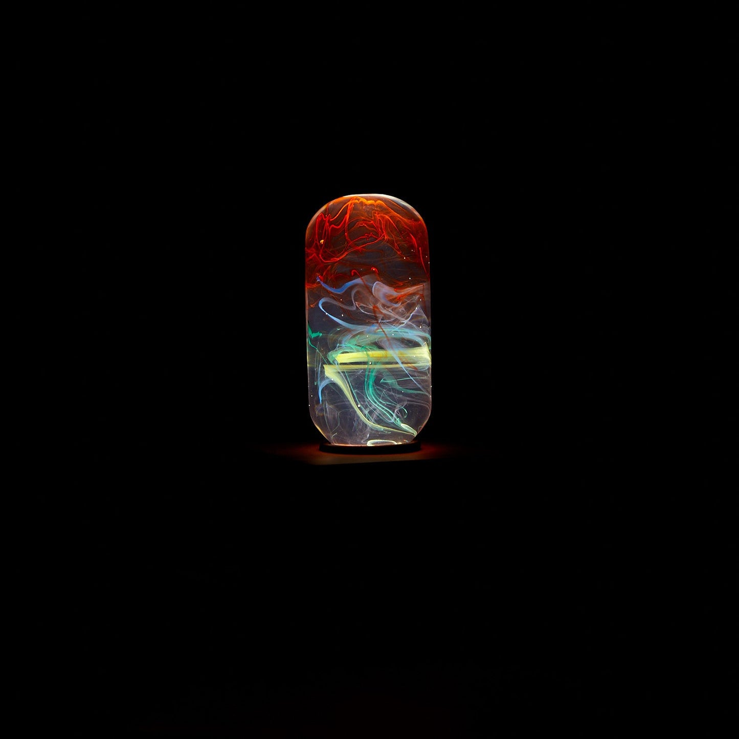 Colorful glass pendant with swirling patterns on a black background