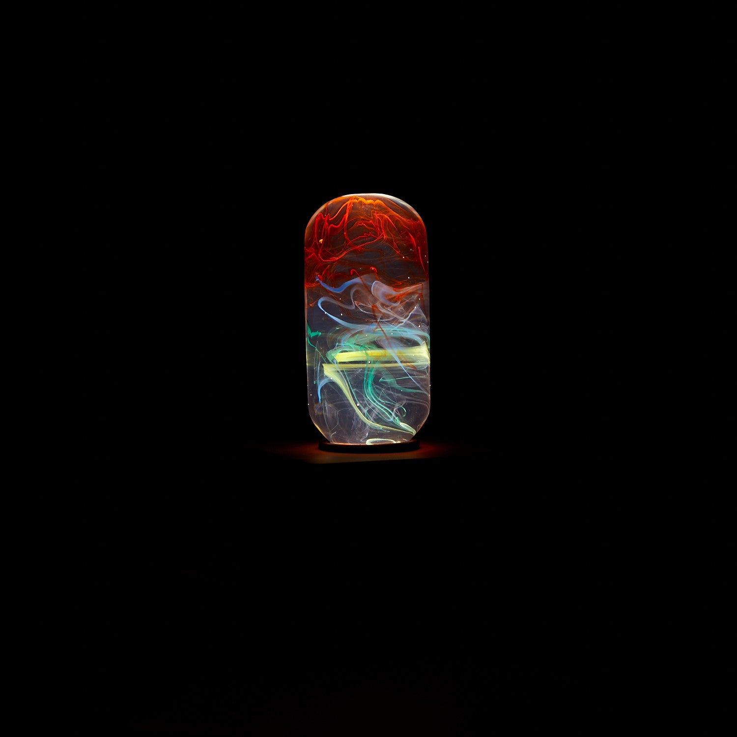 Colorful glass pendant with swirling patterns on a black background