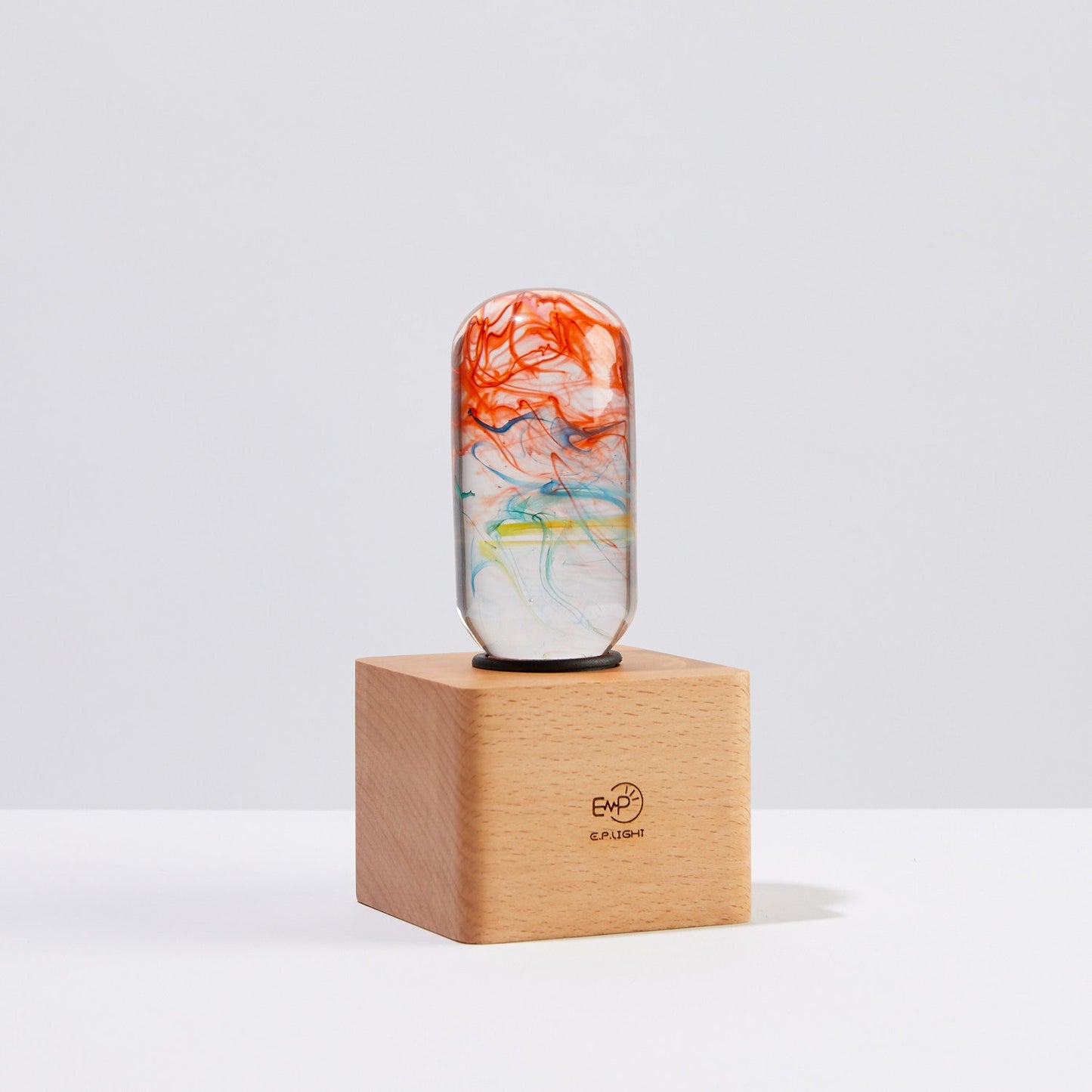 Marble-patterned cylindrical object on a wooden stand with a light gray background