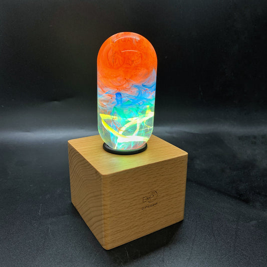 Colorful glass lamp on a wooden base against a dark background